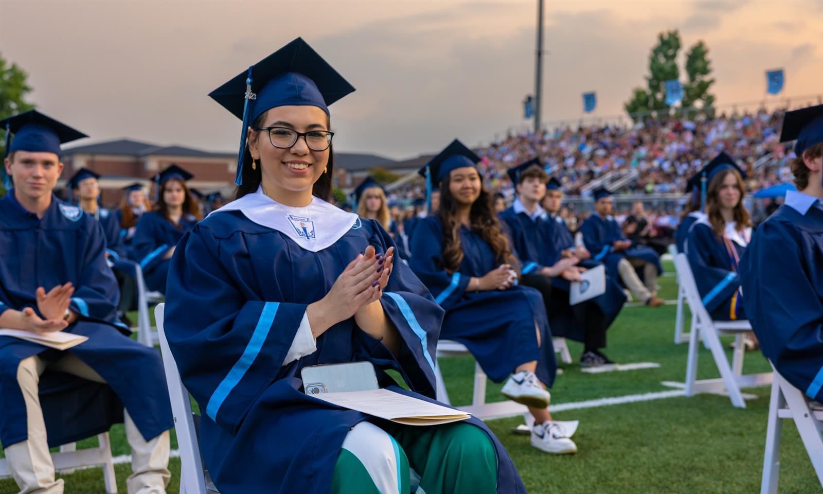 a student in graduation robes sitting at the ceremony